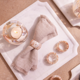 Napkin with rose gold rings and a candle on a textured surface
